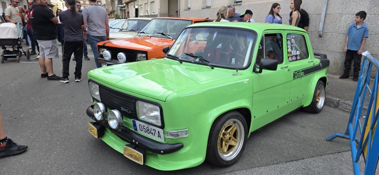 Coche clásico verde en la concentración de Cuatrovientos con público alrededor.