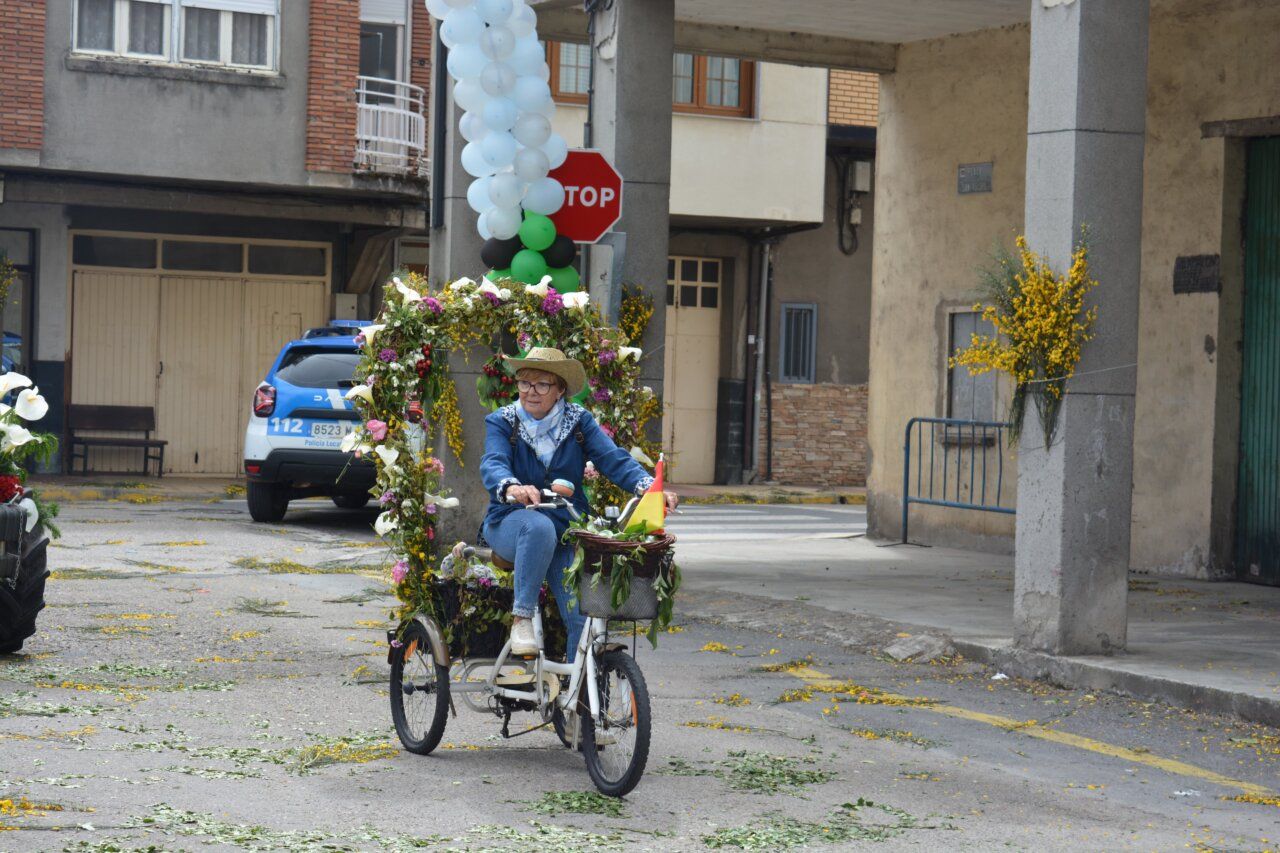 Mujer montando una bicicleta decorada durante la fiesta de San Isidro en Cacabelos