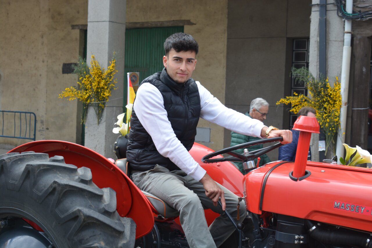 Joven sentado en un tractor rojo durante la fiesta de San Isidro en Cacabelos