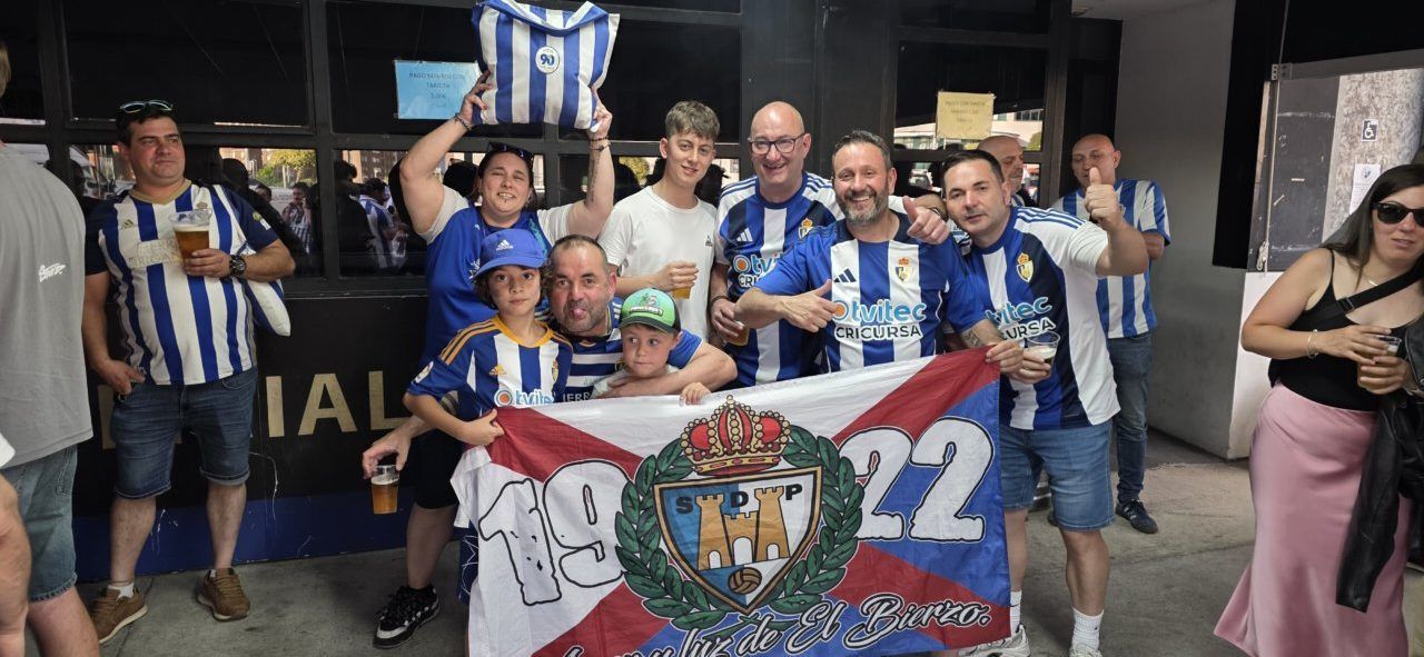 Aficionados de la Ponferradina celebrando en grupo con banderas y camisetas.