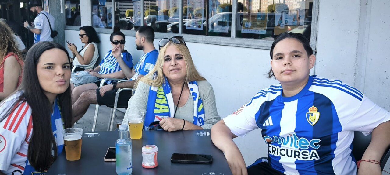 Grupo de aficionados en un bar apoyando al equipo de fútbol.