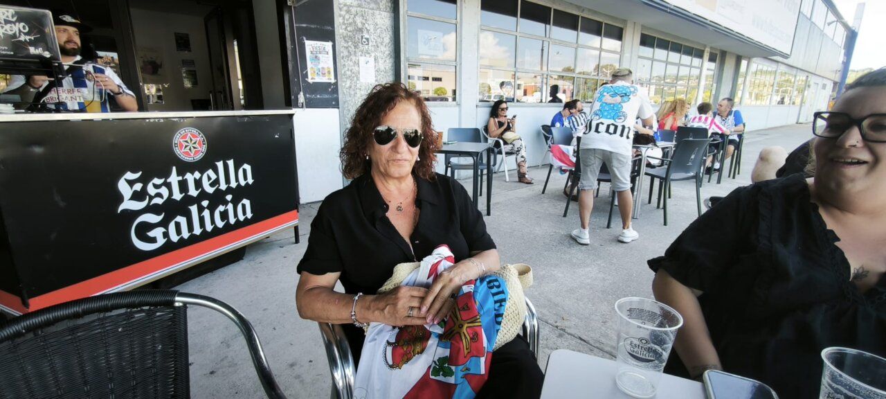 Mujer con gafas de sol en un bar con ambiente deportivo.