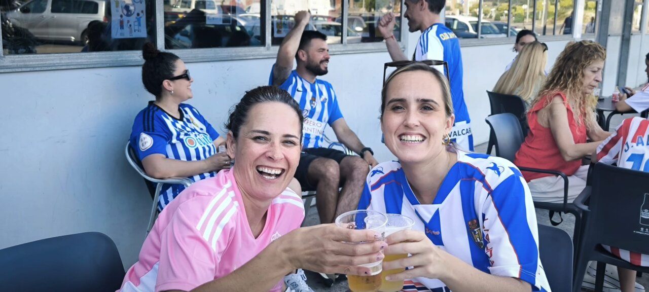 Dos mujeres sonrientes brindando con cervezas en un bar
