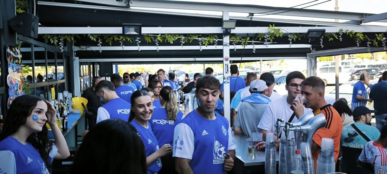 Grupo de aficionados en un bar animado con camisetas azules