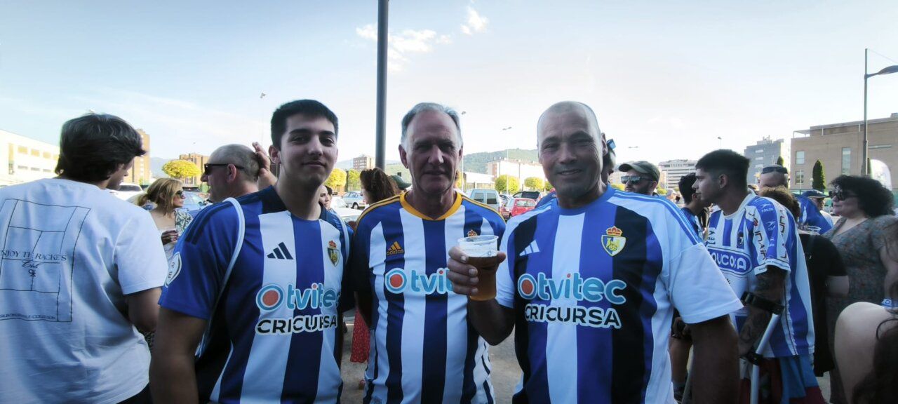 Tres aficionados posando en un bar con camisetas de fútbol