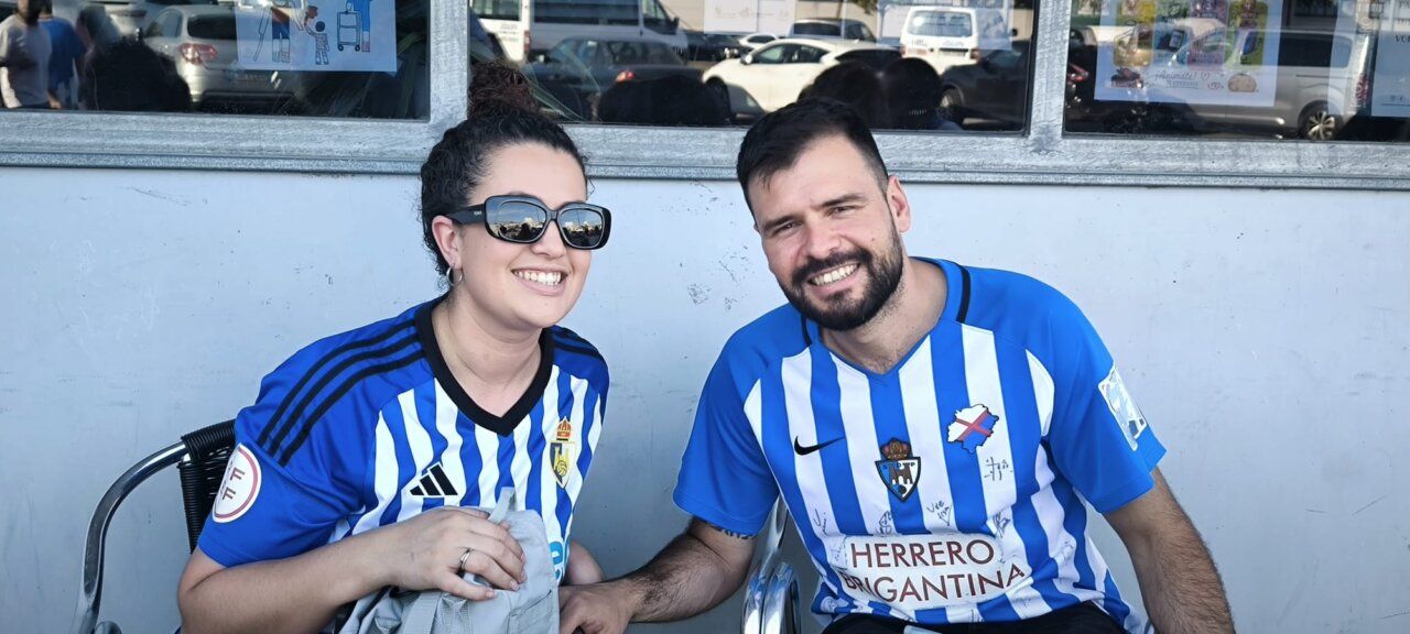 Pareja sonriente en un bar vistiendo camisetas de fútbol