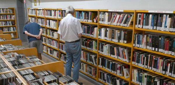Personas revisando estantes de libros en una biblioteca