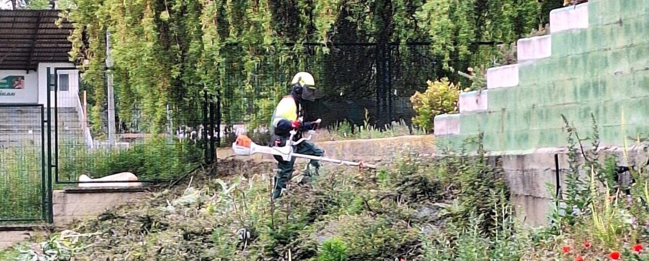 Trabajador realizando labores de jardinería en piscinas municipales de Toreno