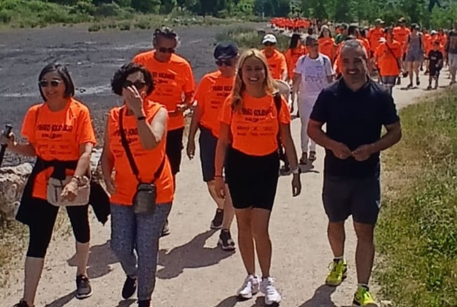 Grupo de personas caminando en un evento solidario con camisetas naranjas