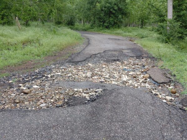 Camino en Dehesas con deterioro y piedras visibles en la superficie