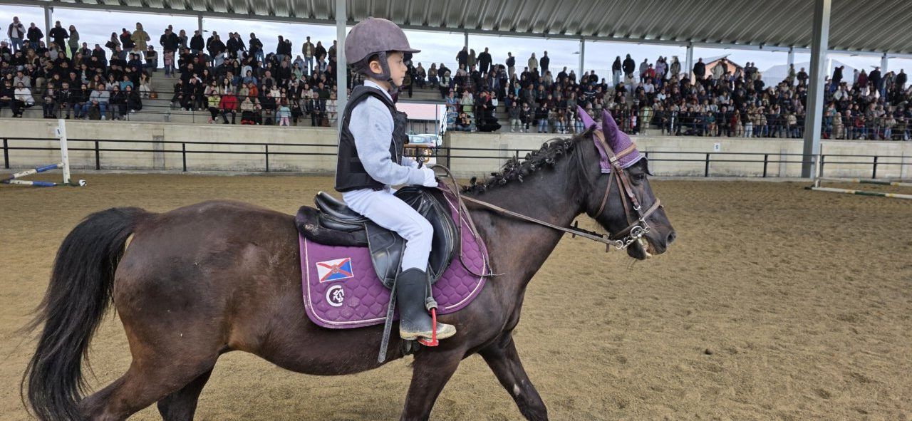 Niño montando un caballo en una exhibición de saltos en Camponaraya
