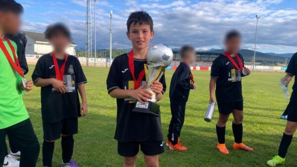 Niño sosteniendo un trofeo tras ganar un torneo de fútbol