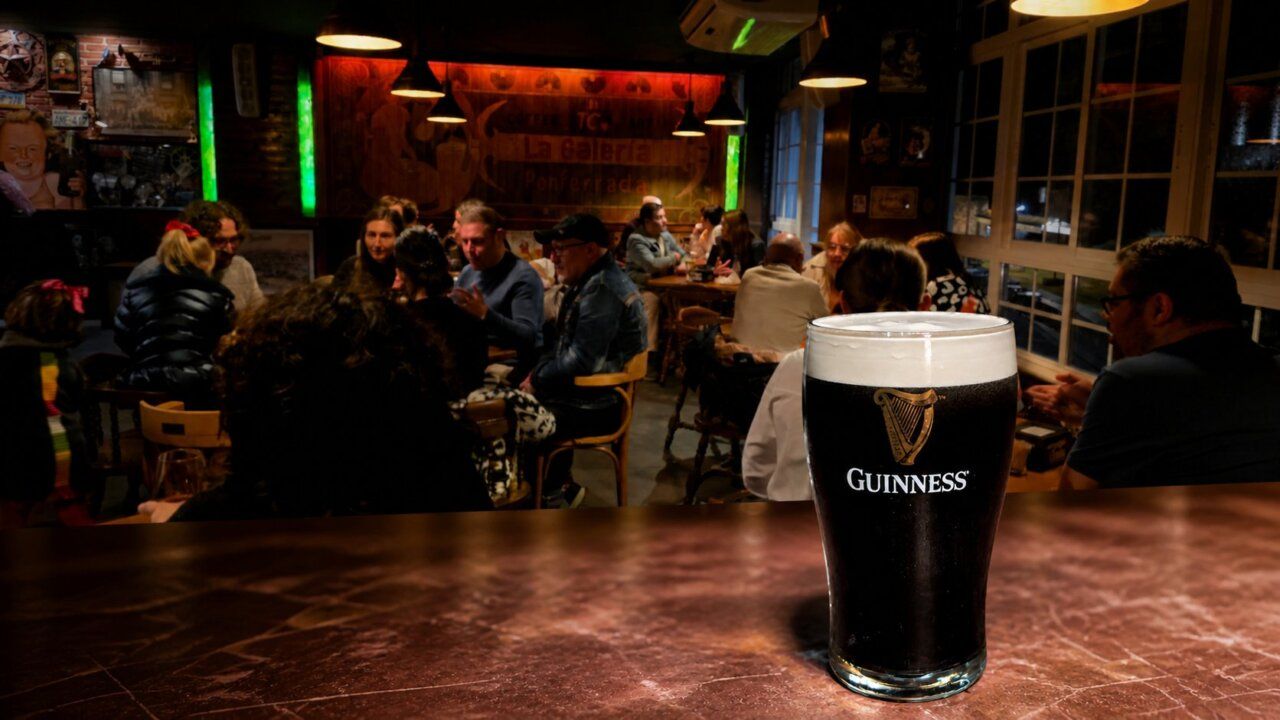 Una pinta de cerveza Guinness en un bar con gente disfrutando