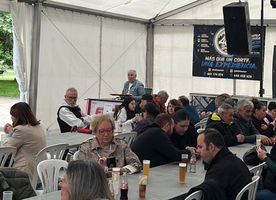 Personas reunidas en un evento a favor de OncoBierzo bajo una carpa.