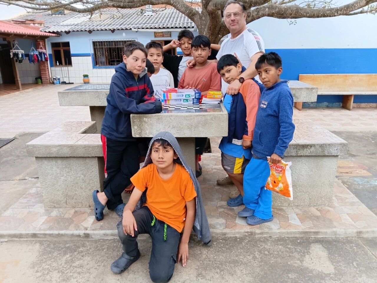 Grupo de niños y un adulto en una mesa al aire libre en Bolivia.