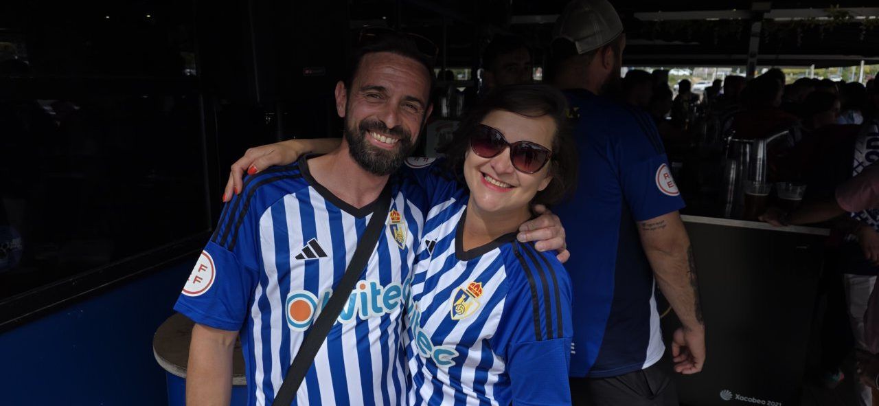 Pareja sonriente con camisetas del equipo en un bar