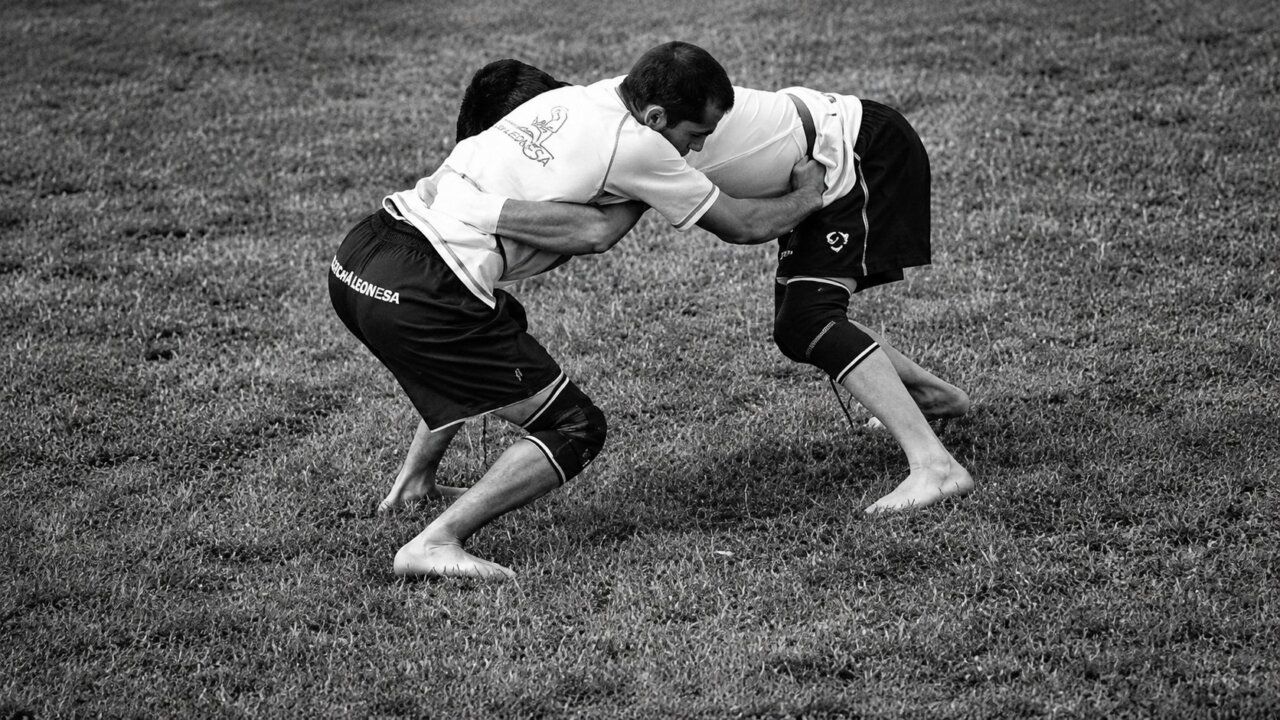 Dos luchadores en un combate de lucha leonesa en el campo