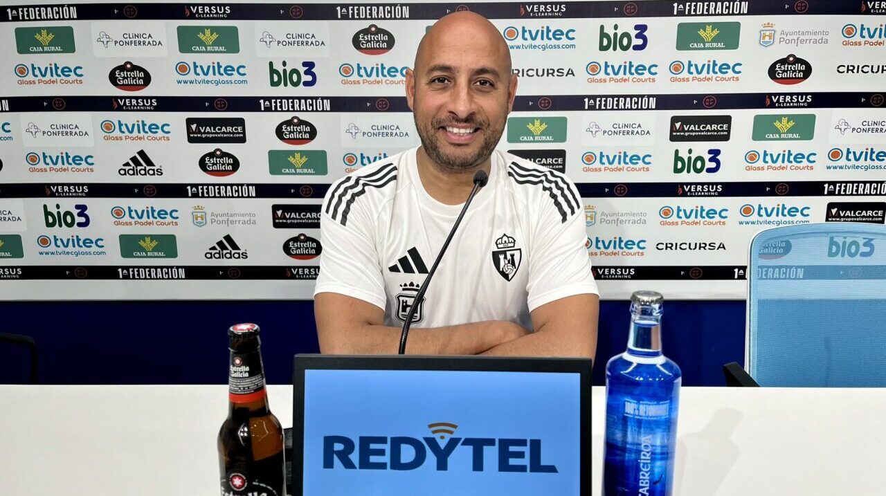 Entrenador Mehdi Nafti en rueda de prensa con bebidas en la mesa