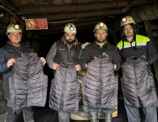 Cuatro mineros sosteniendo chalecos calefactores en la mina