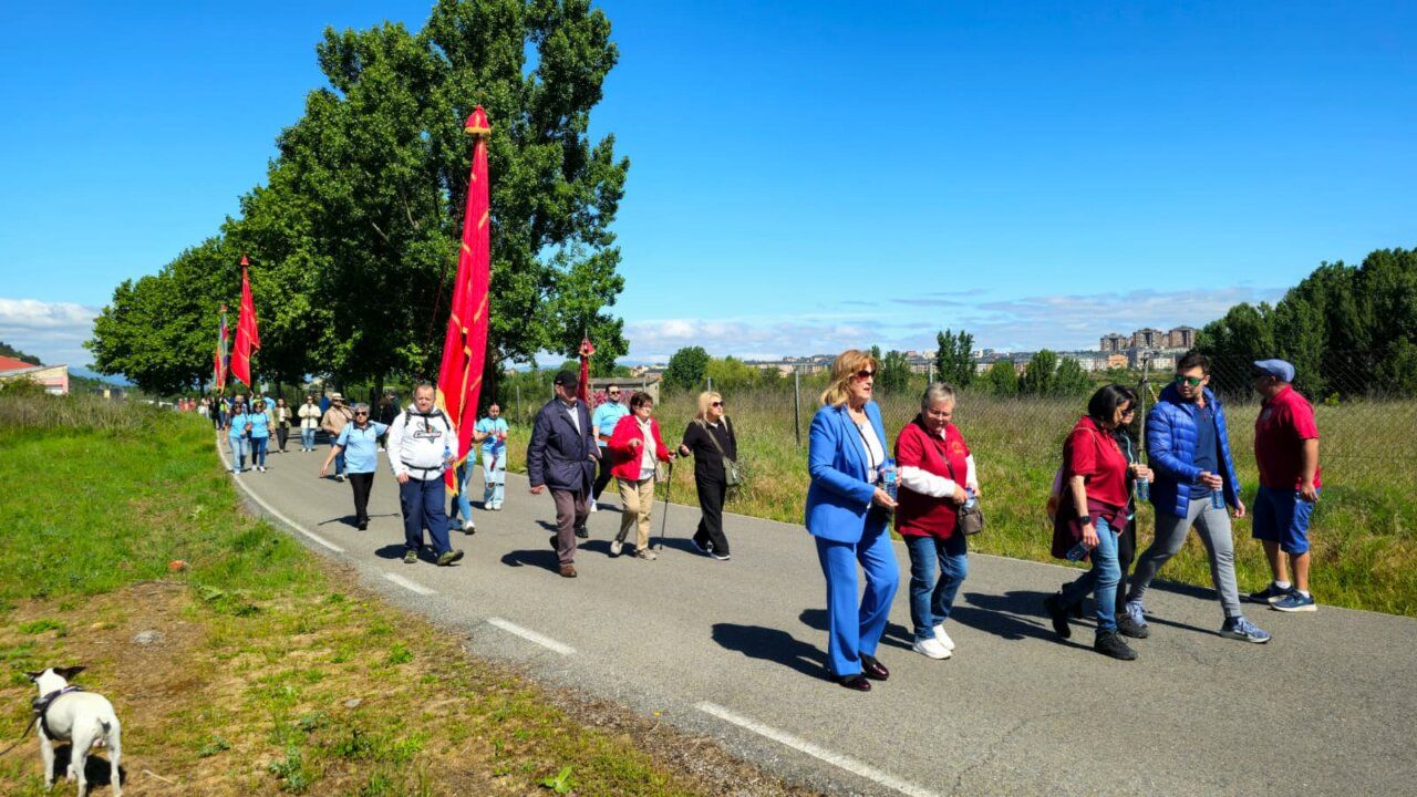 Grupo de personas caminando con pendones en la romería de San Isidro