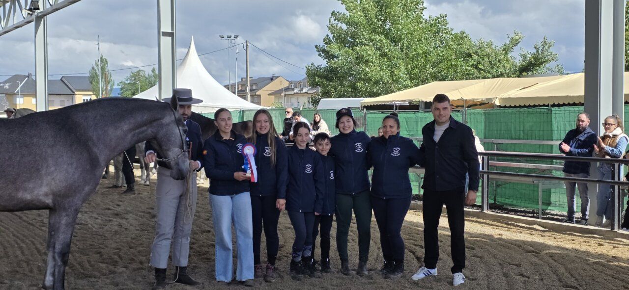 Grupo de personas en evento ecuestre con caballo y trofeo.