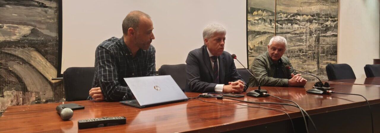 Tres personas sentadas en una mesa durante la proyección de un documental