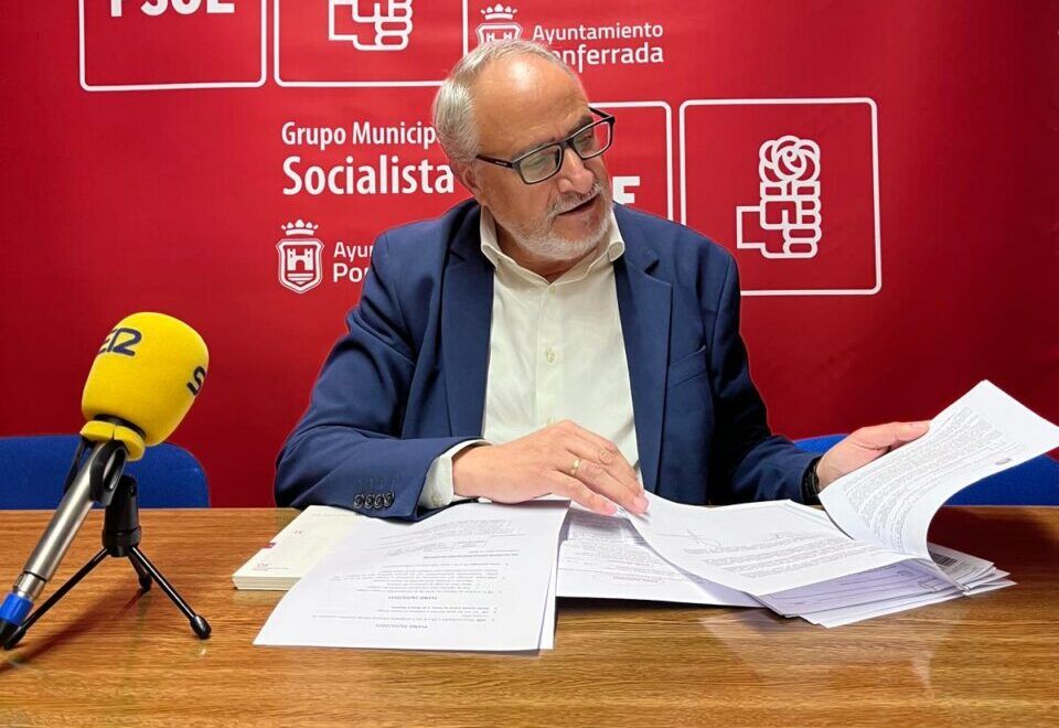 Miembro del PSOE revisando documentos en una mesa con fondo rojo