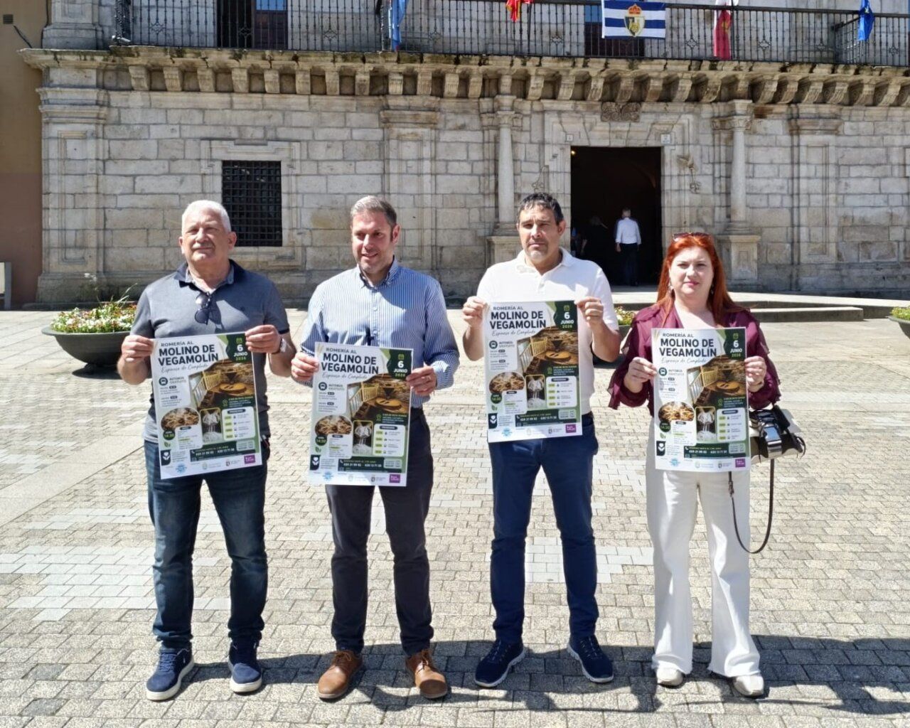 Cuatro personas sosteniendo carteles de la Romería al Molino de Vegamolín