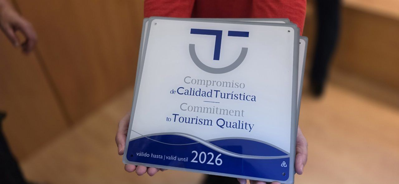 Persona sosteniendo un cartel de compromiso de calidad turística