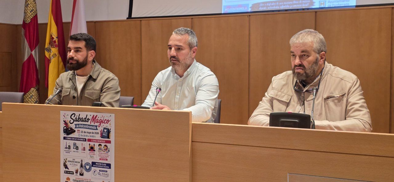 Tres personas sentadas en una mesa durante un evento llamado Sábado Mágico