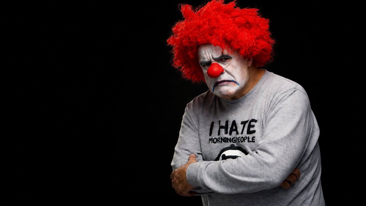 Actor con peluca roja y maquillaje de payaso en escena teatral