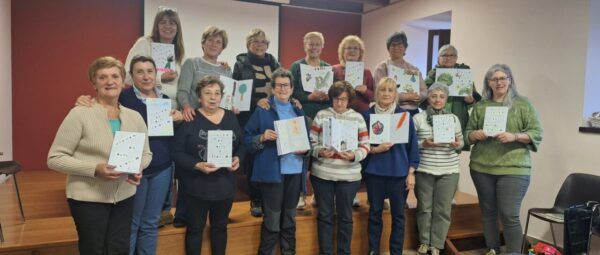 Grupo de mujeres sosteniendo libros en un taller de arte comunitario
