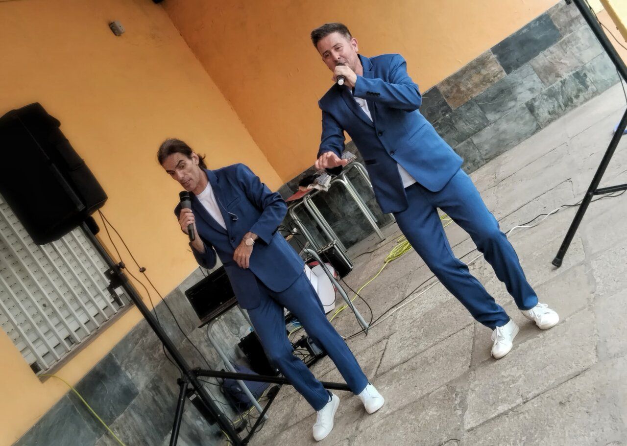 Dos cantantes en trajes azules actuando en un bar
