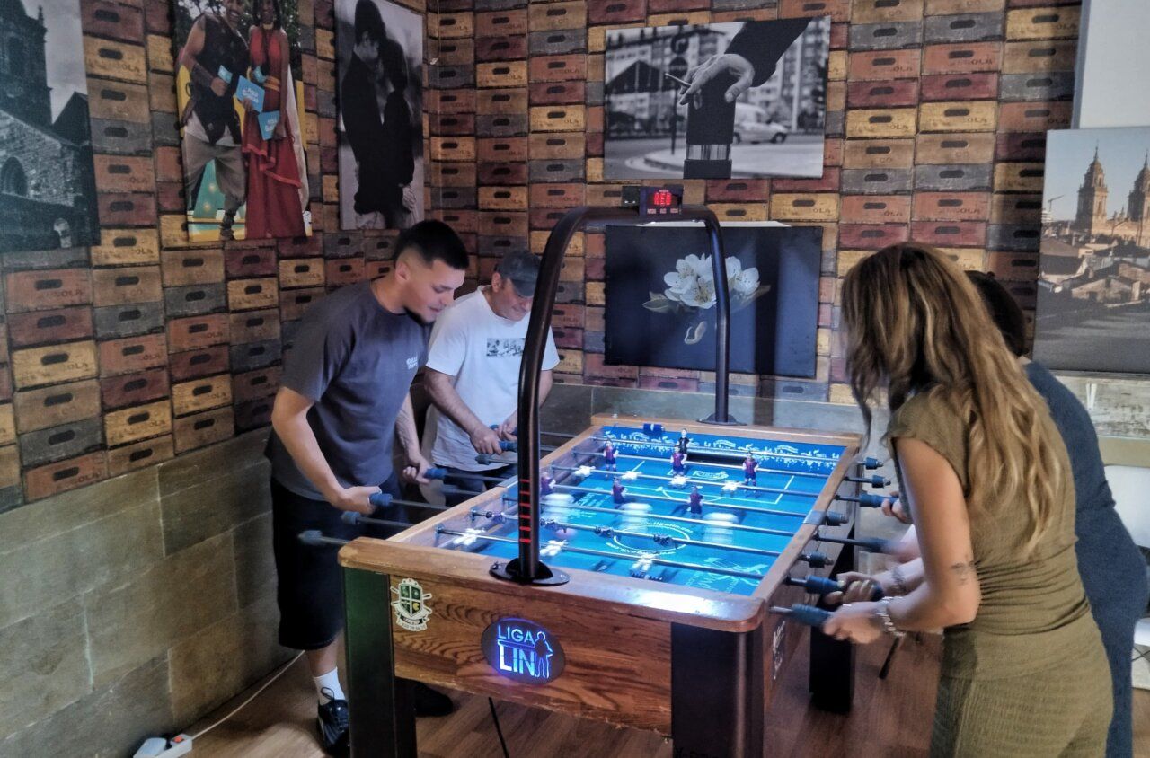 Personas jugando al futbolín en el Bar Central durante un tardeo.
