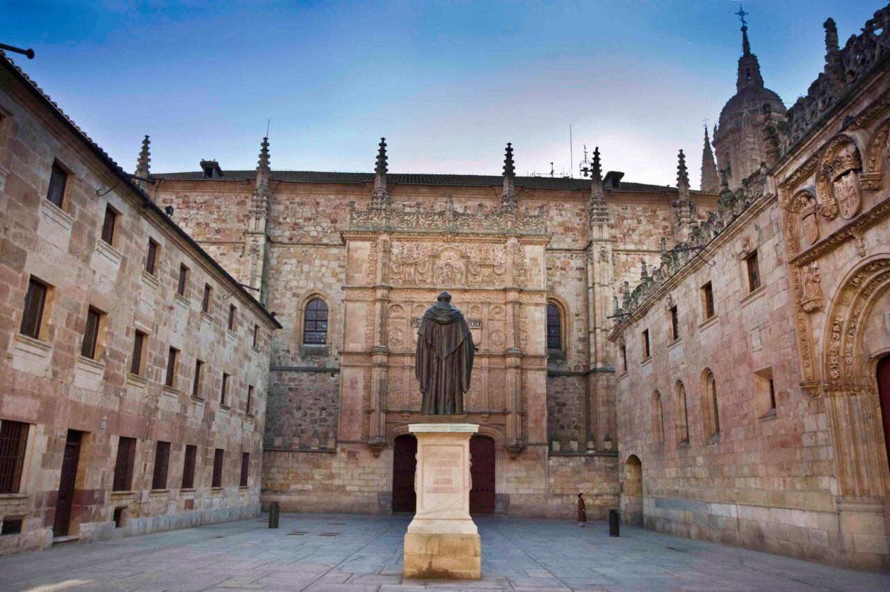 Estatua en el patio de la Universidad de Salamanca con arquitectura histórica.
