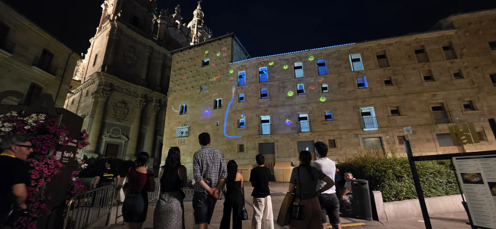 Personas observando un videojuego interactivo en la fachada de un edificio en Salamanca