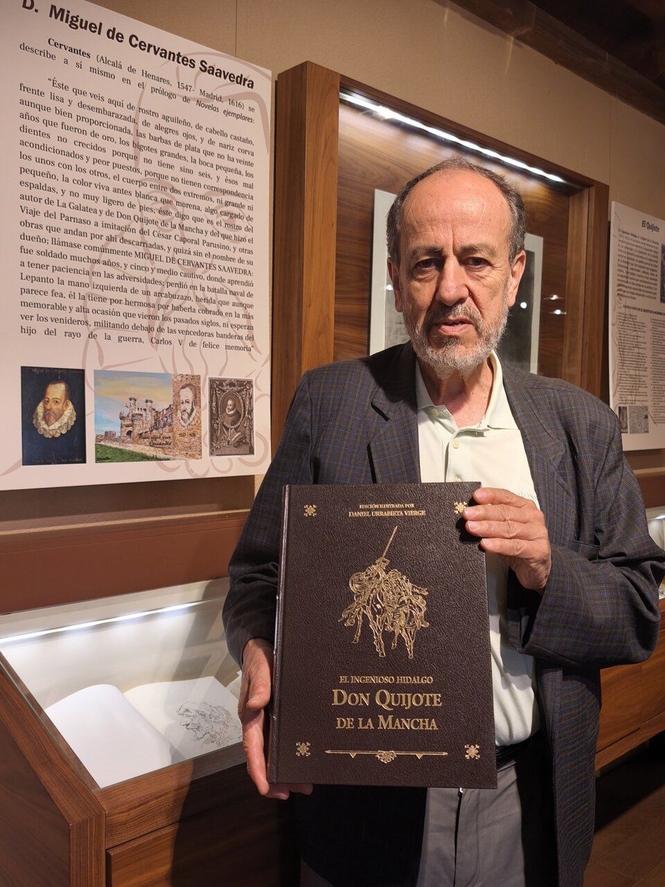 Hombre sosteniendo una edición de Don Quijote en una exposición