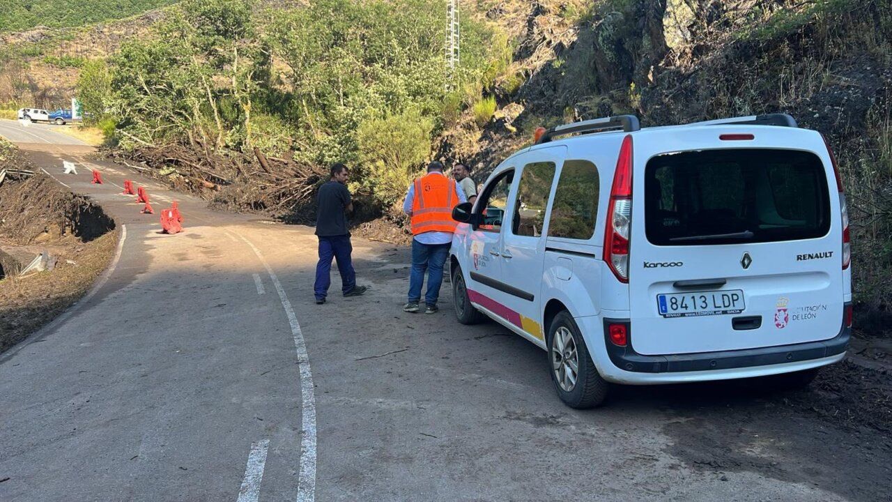 Carretera de acceso a Fornela cerrada tras una riada con trabajadores evaluando daños.