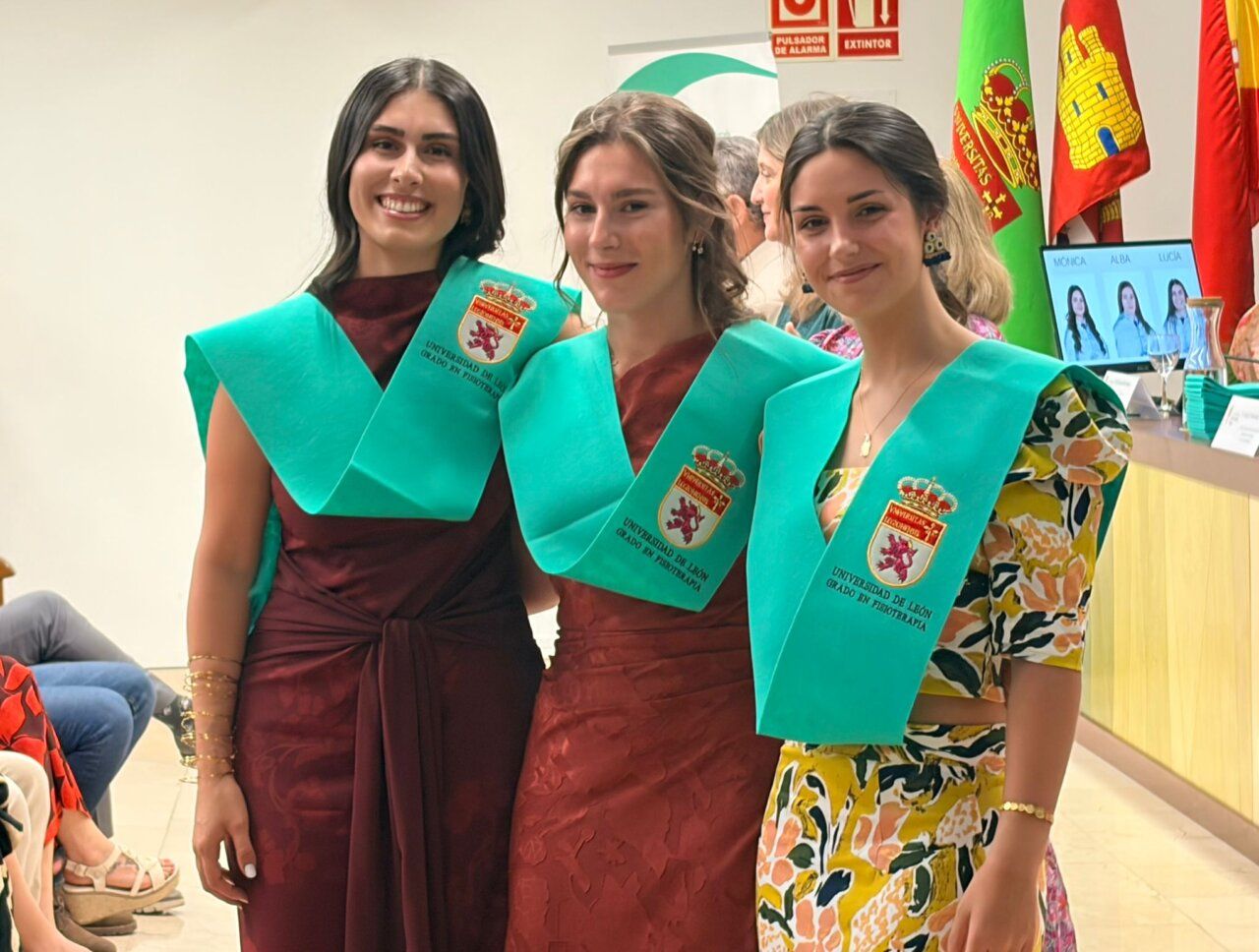 Tres graduadas de fisioterapia posando con togas en el Campus de Ponferrada