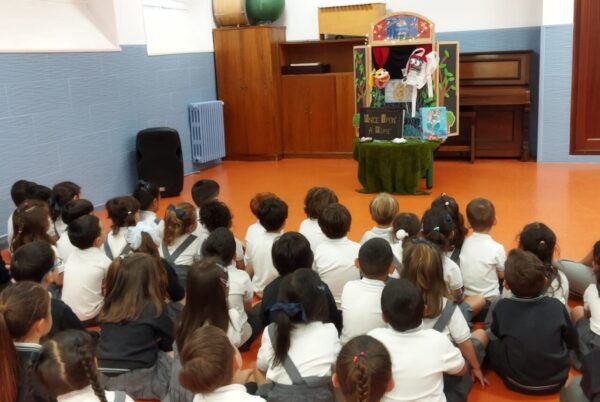 Niños sentados frente a un teatro de marionetas en un taller escolar