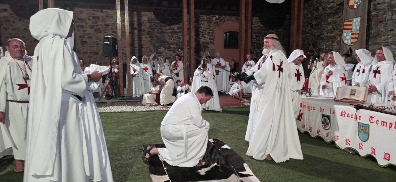 Ceremonia de ordenación templaria en el Castillo de Ponferrada con participantes vestidos de blanco.