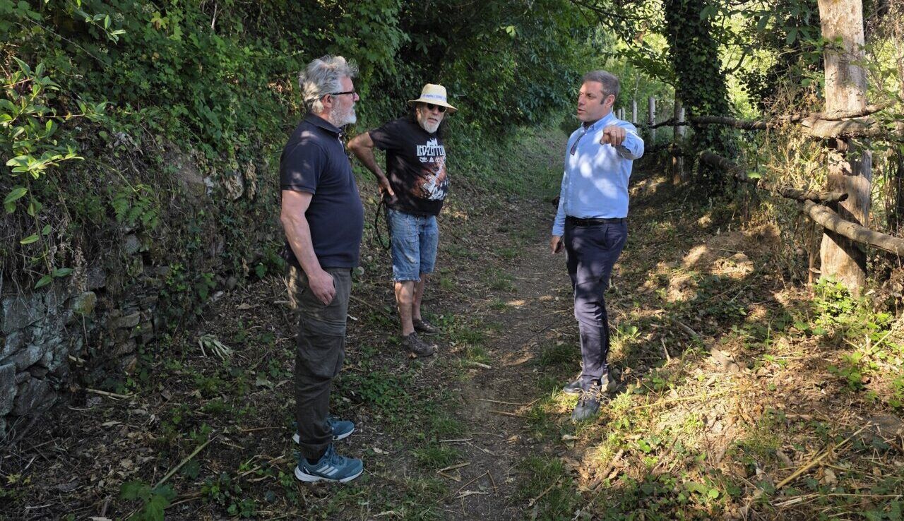 Tres personas discutiendo en un sendero rodeado de vegetación