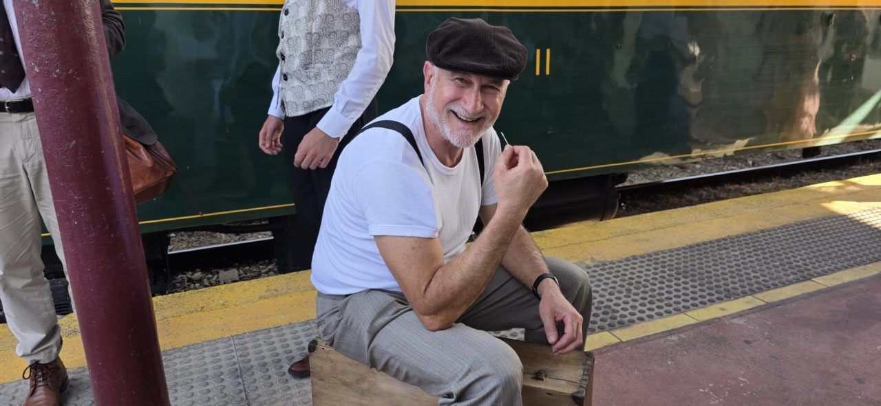 Hombre sonriente vestido de época en estación de tren