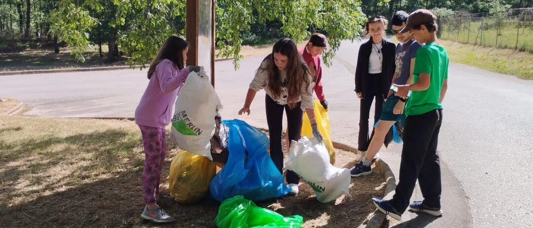 Estudiantes recogiendo residuos en un entorno natural durante una actividad ambiental.