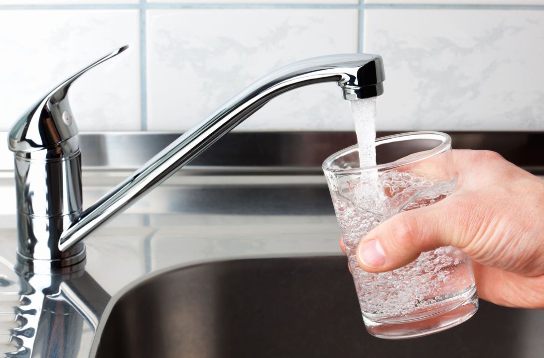 Grifo de cocina vertiendo agua en un vaso transparente