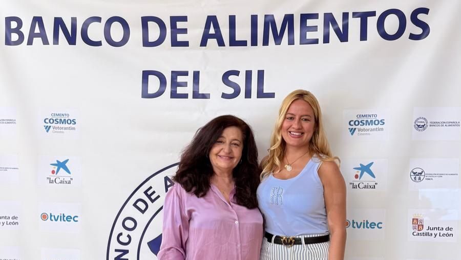 Dos mujeres posando frente a un cartel del Banco de Alimentos del Sil