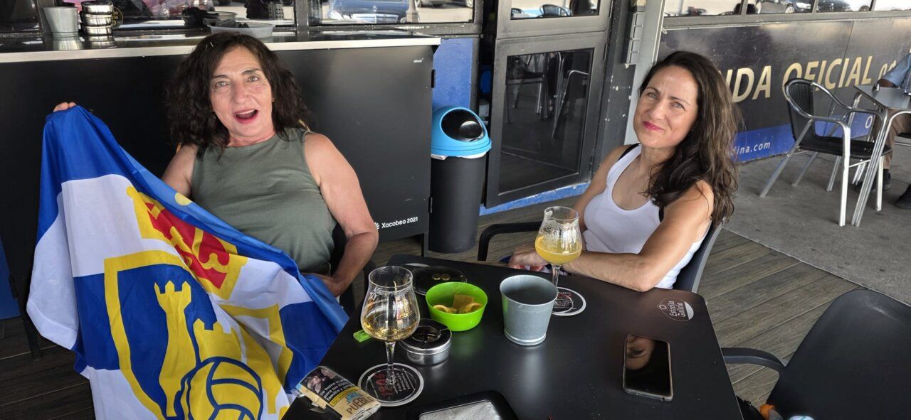 Dos mujeres en un bar sosteniendo una bandera de la Ponferradina