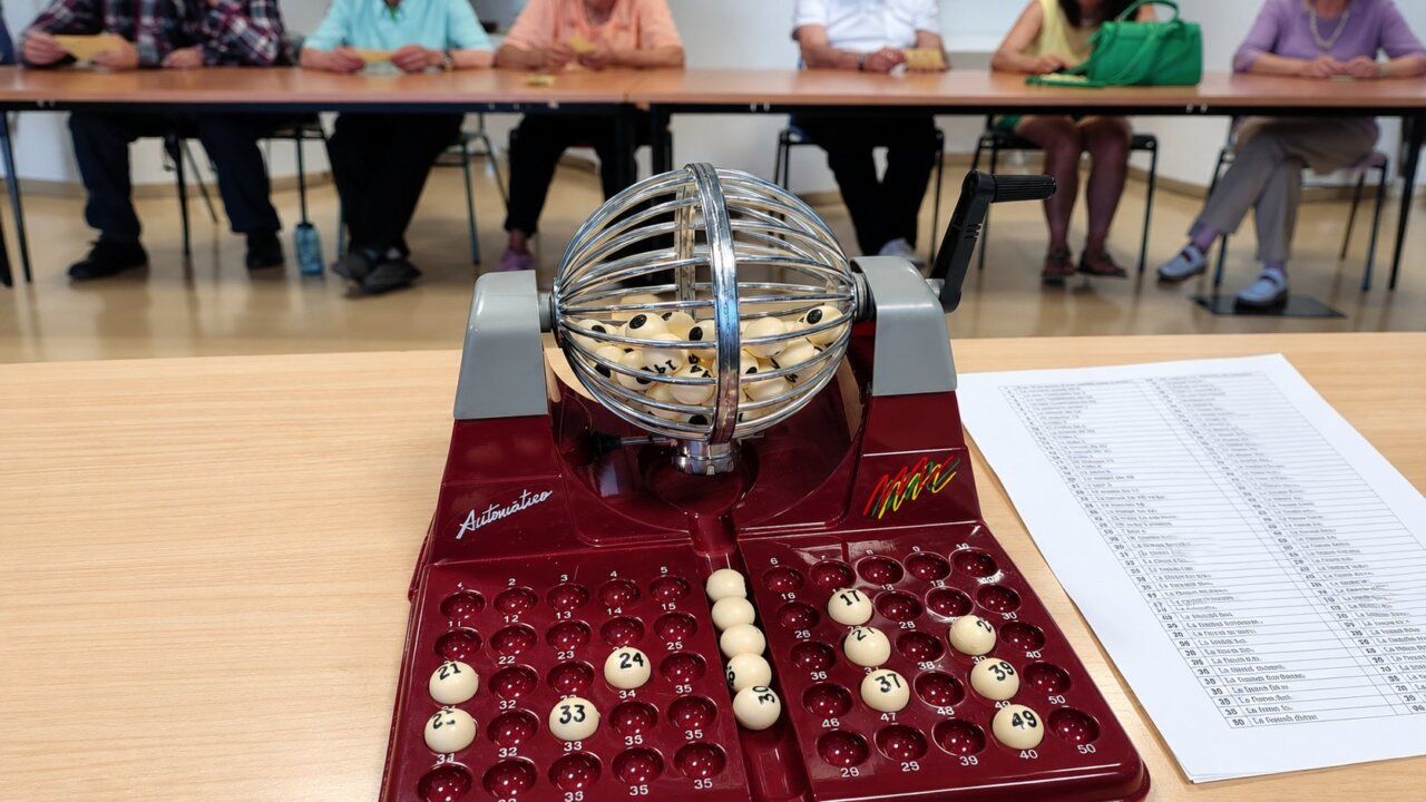 Máquina de bingo con bolas numeradas y participantes en el fondo