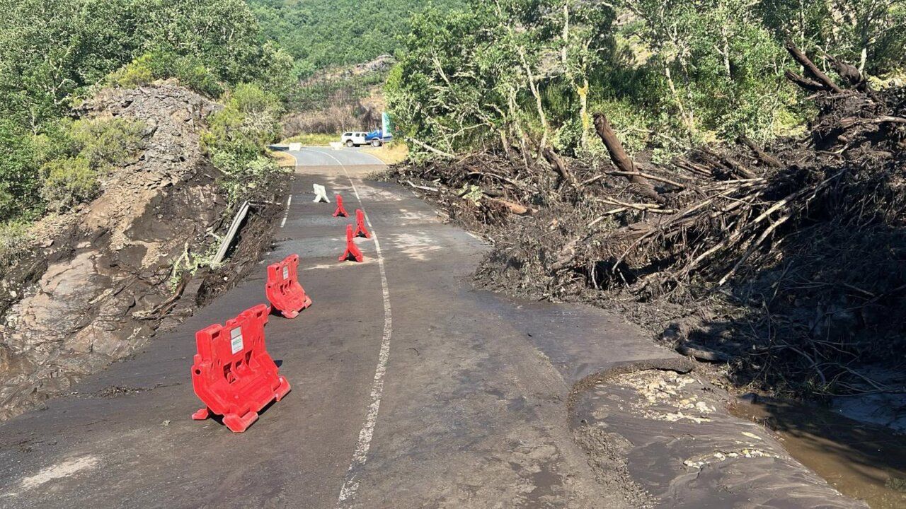 Carretera de acceso a Fornela cerrada tras una riada con obstáculos visibles