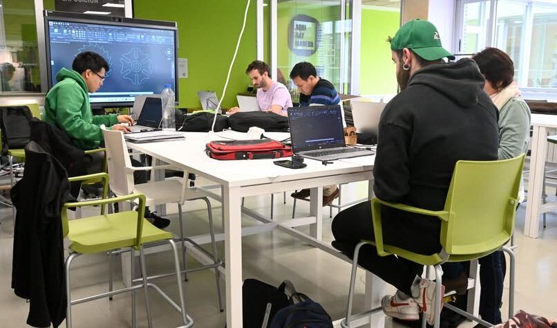 Estudiantes trabajando en un aula moderna con computadoras portátiles